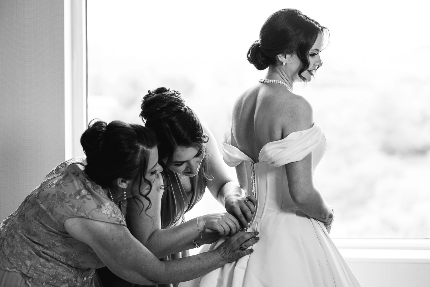 Black and white intimate moments of wedding dress preparation.