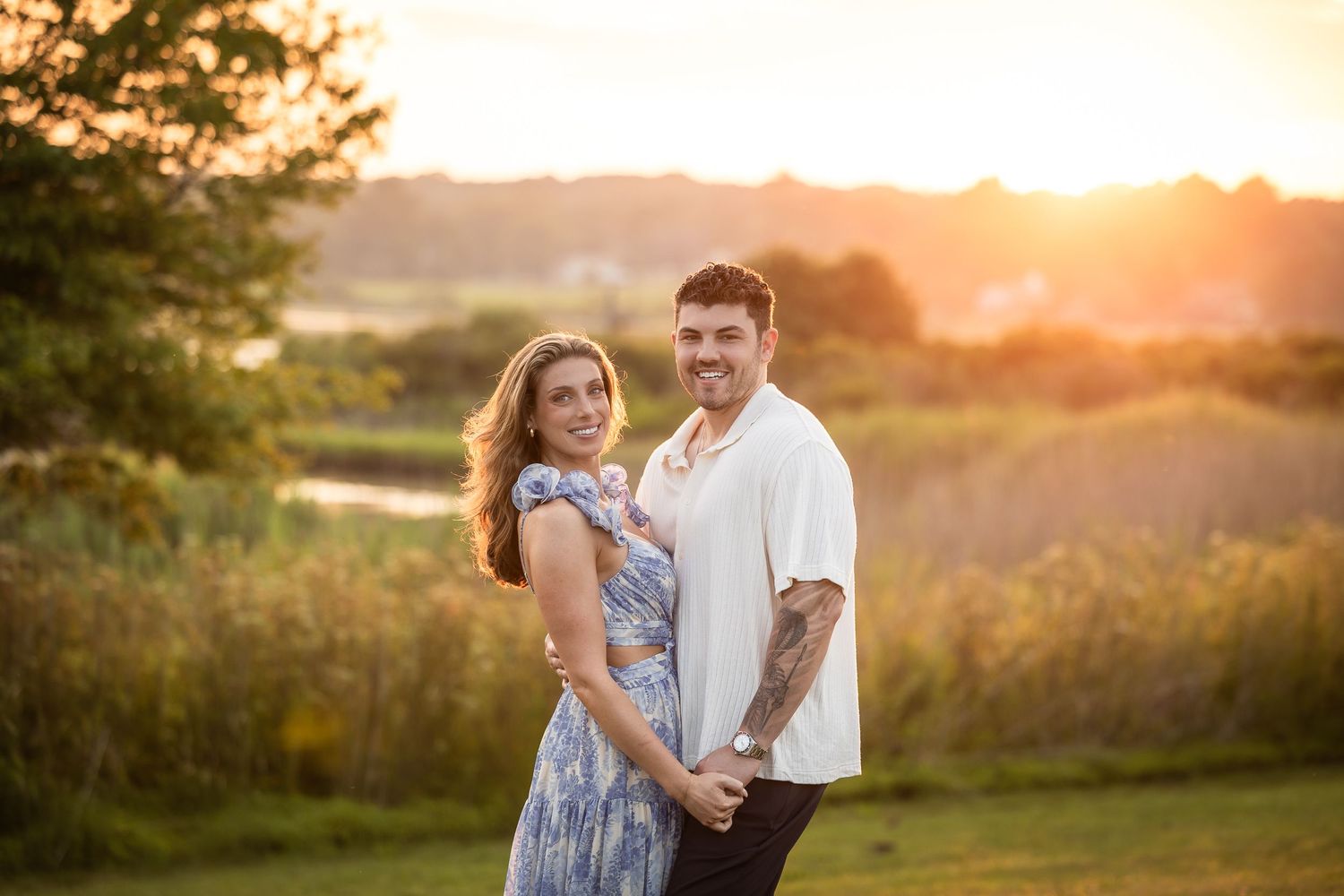 Couple enjoying a romantic sunset photoshoot in a golden field with warm summer lighting.