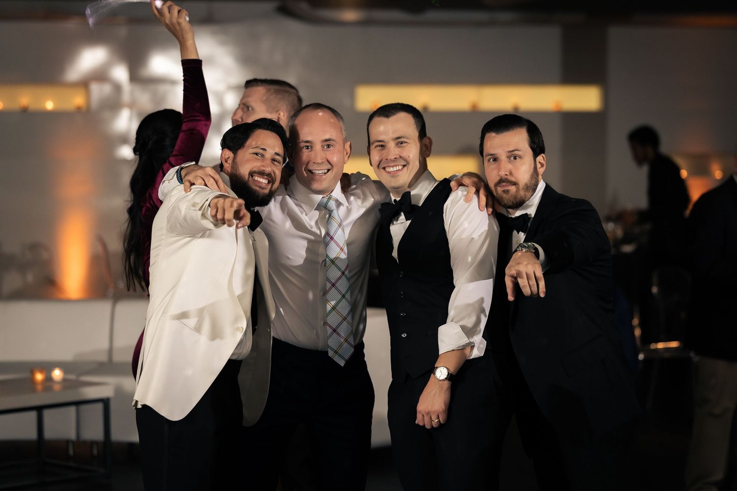 A group of people celebrate and pose together at a dimly lit indoor event or party.