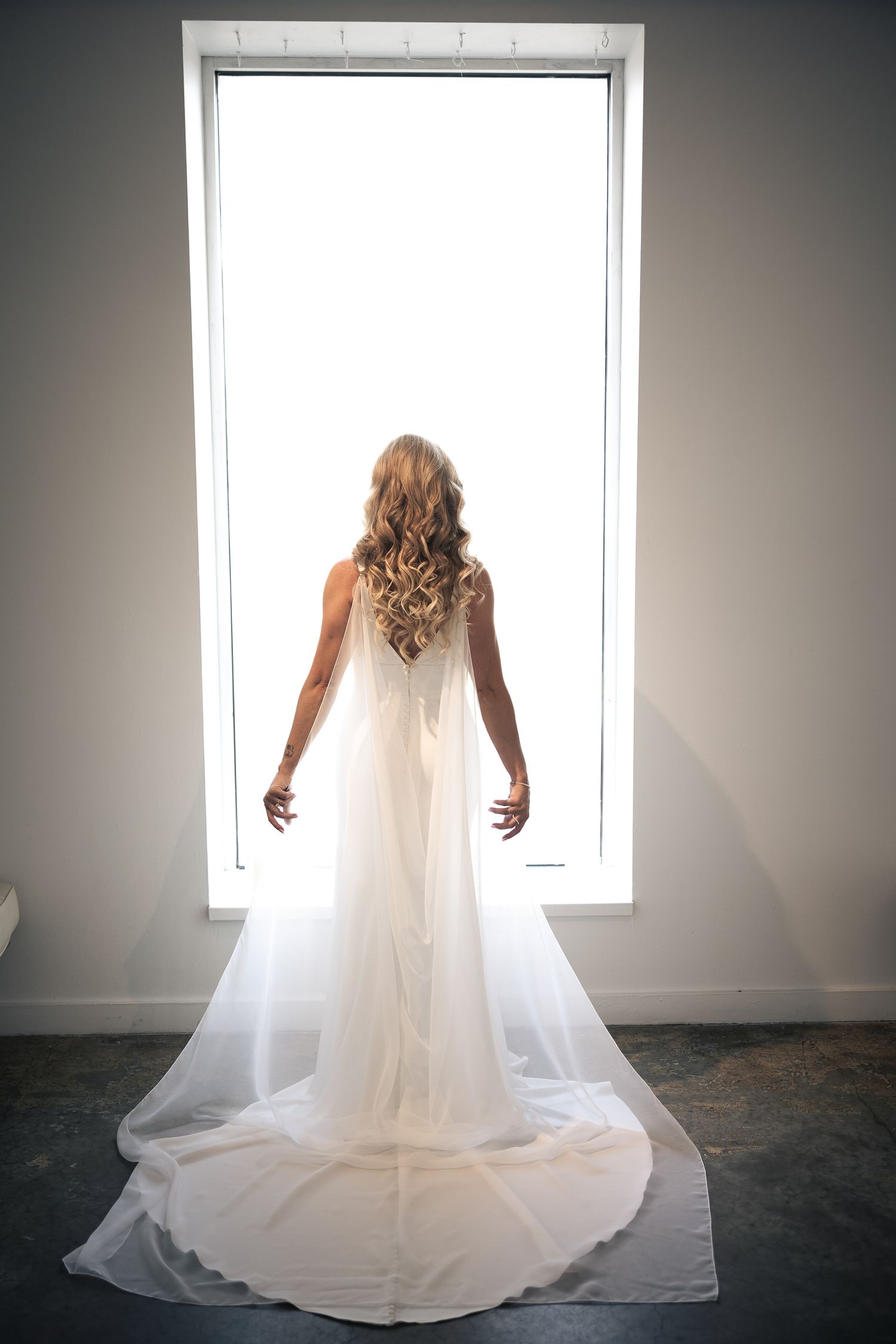 A series of wedding dress photos showing the flowing train and veil against a bright window in a minimalist setting.