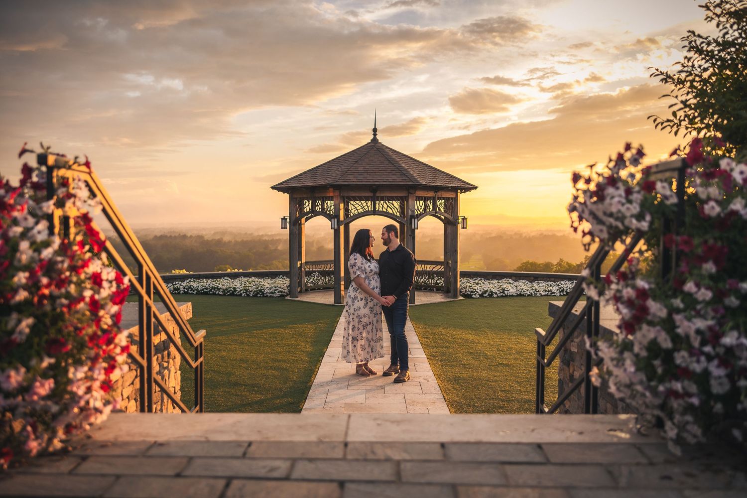 A romantic gazebo scene at golden hour with floral arrangements and dramatic sunset sky.