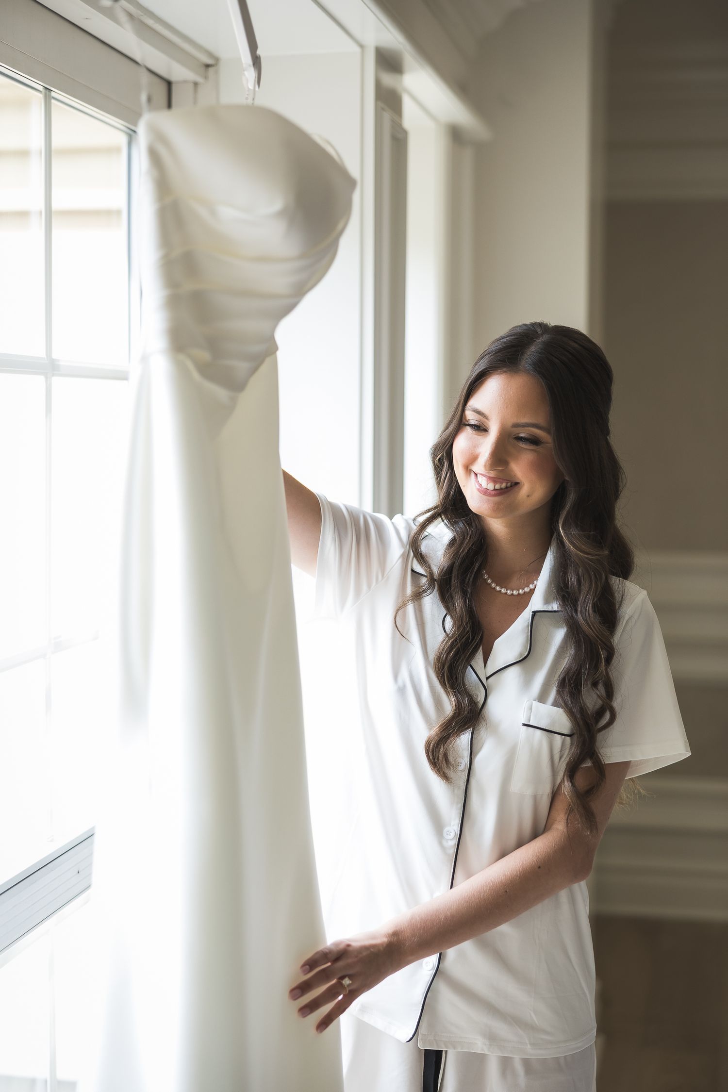 Bridal preparation photos in bright white room with natural window light.
