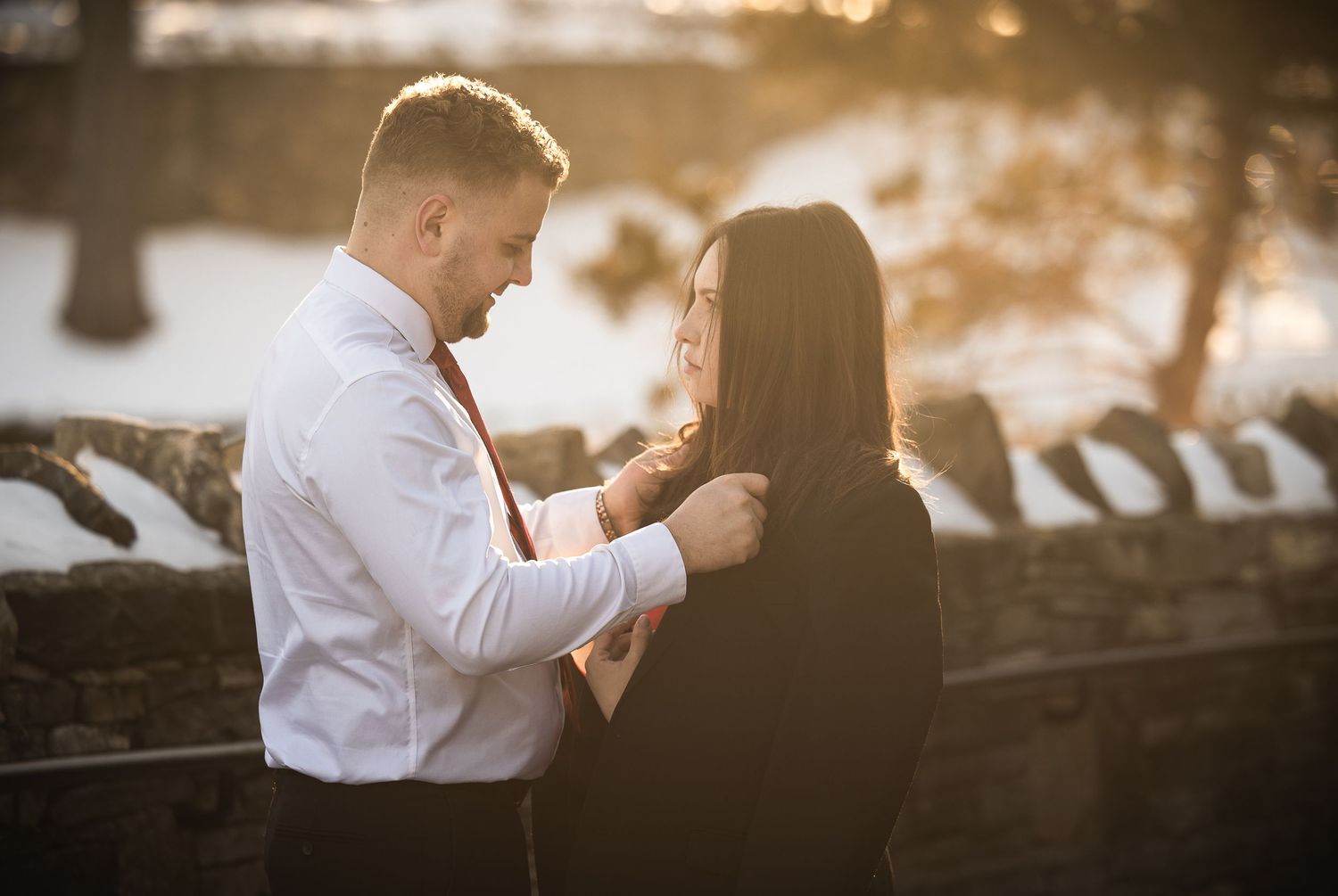 A romantic couple embraces during a golden sunset photoshoot in a scenic outdoor setting.