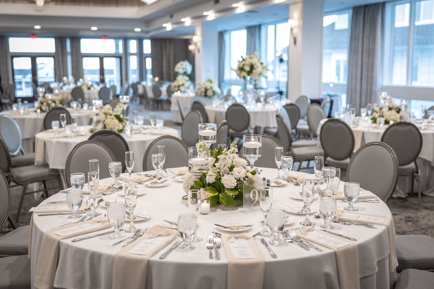 Elegant wedding reception venue with round tables set with formal place settings.