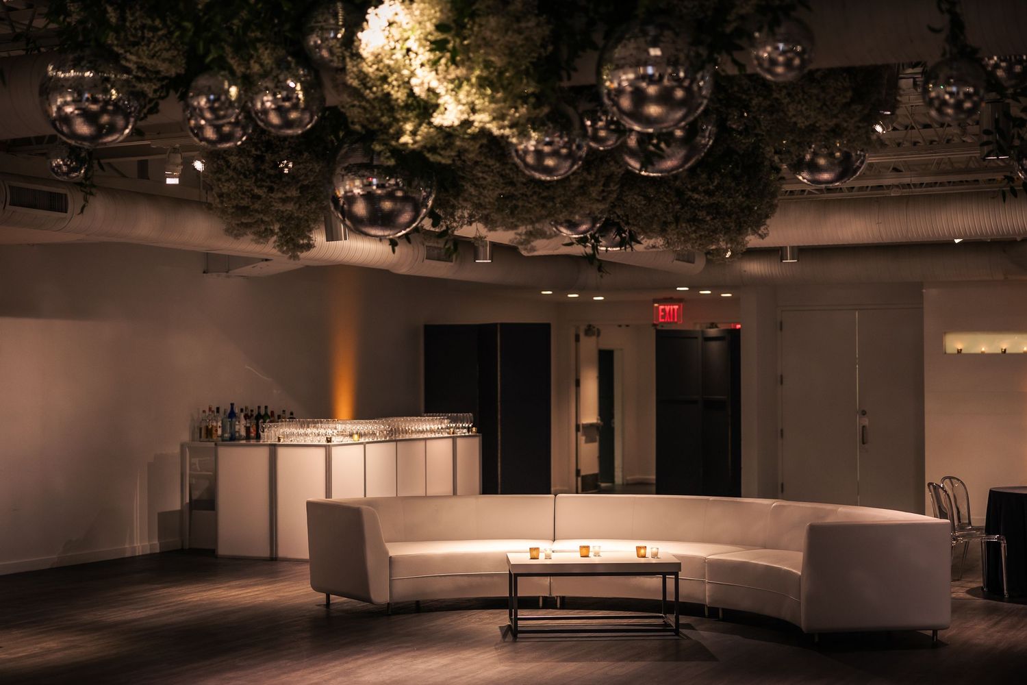 A modern office space with warm lighting features a curved reception desk and minimalist interior design elements.