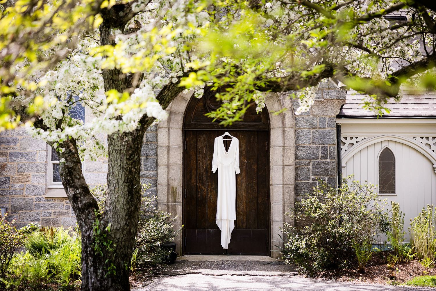 A serene stone archway walkway surrounded by blooming spring trees and historic architecture.