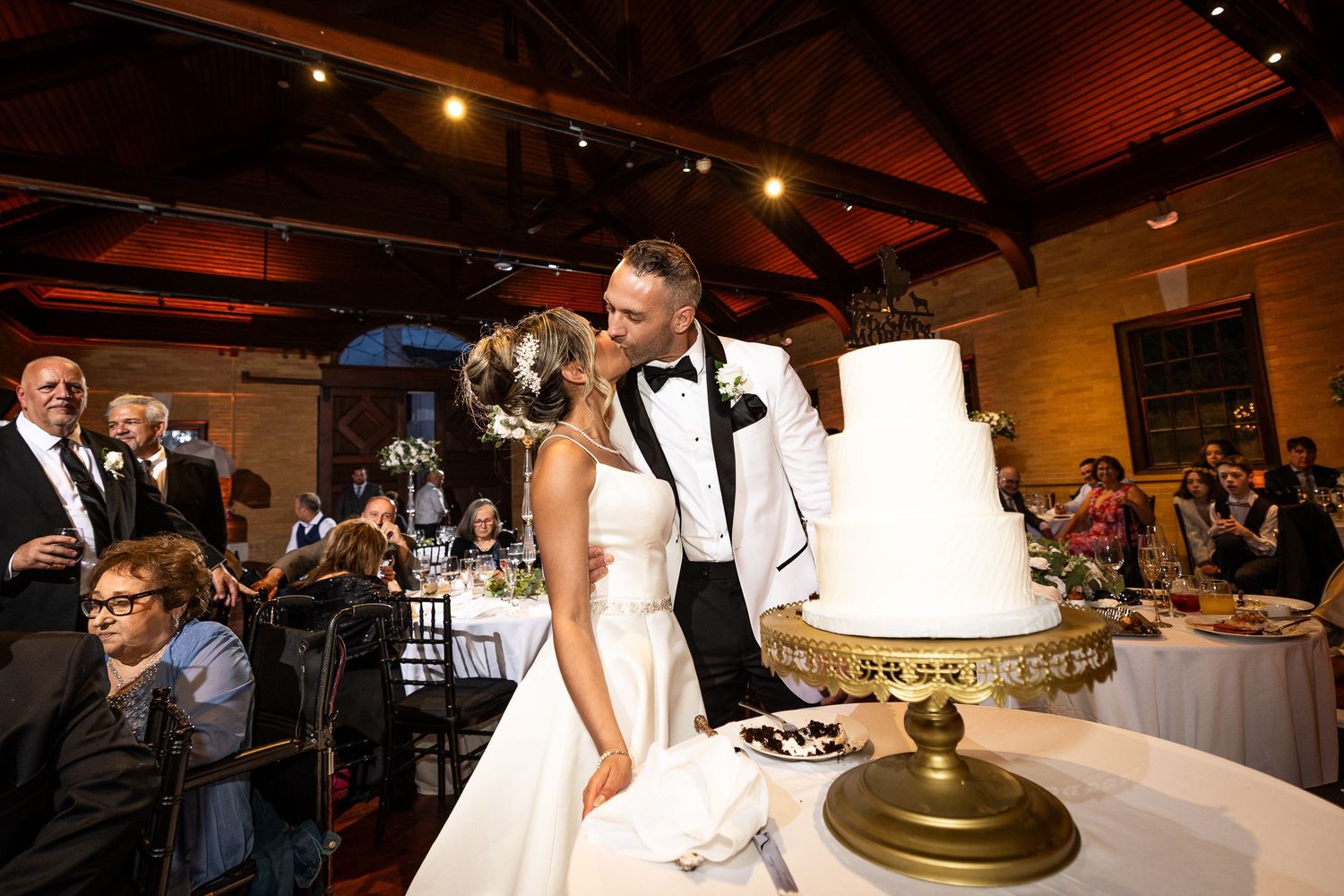 Wedding reception venue with rustic wooden beams and warm ambient lighting.