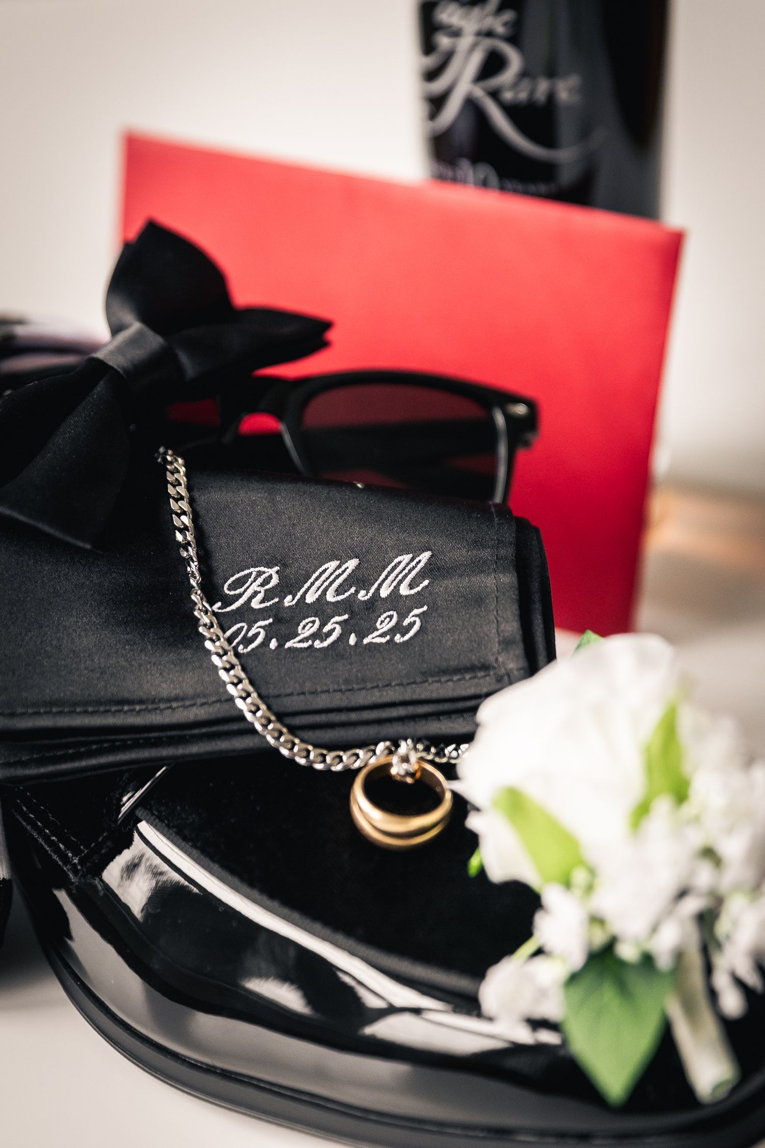 Elegant black dress shoes with monogrammed details displayed against red background.