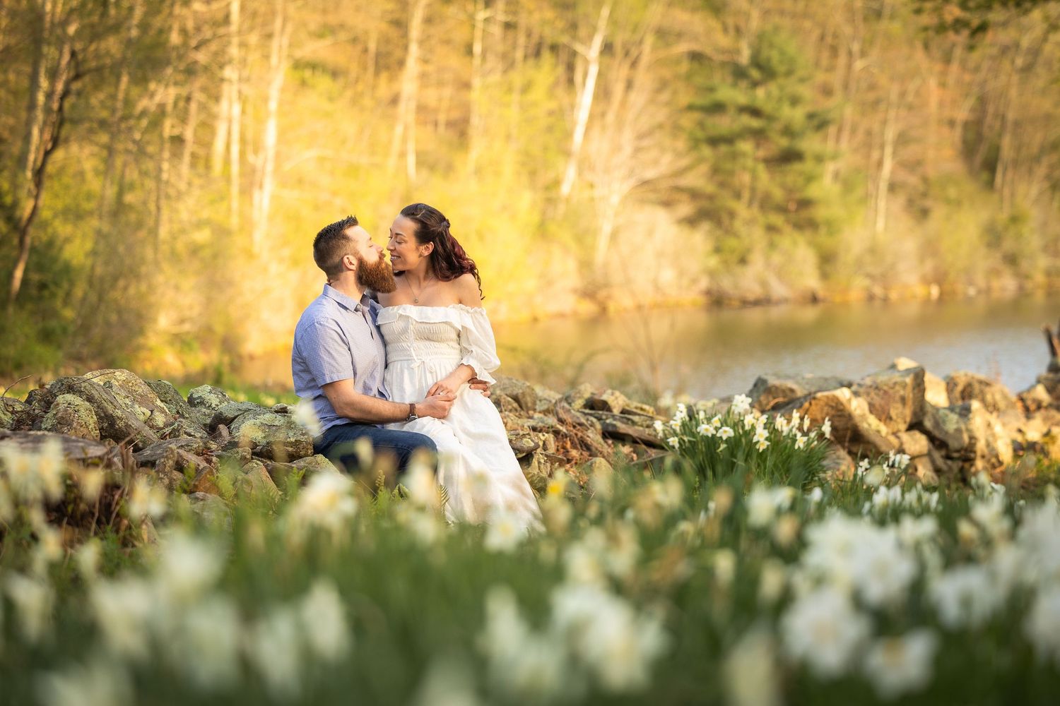 A couple shares a romantic moment while sitting together in a scenic outdoor setting during golden hour.