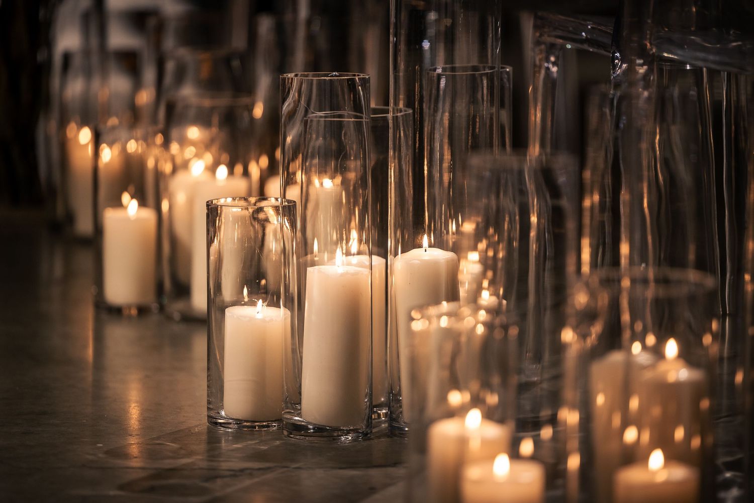 Rows of glowing white candles in glass holders create a romantic and atmospheric lighting display.