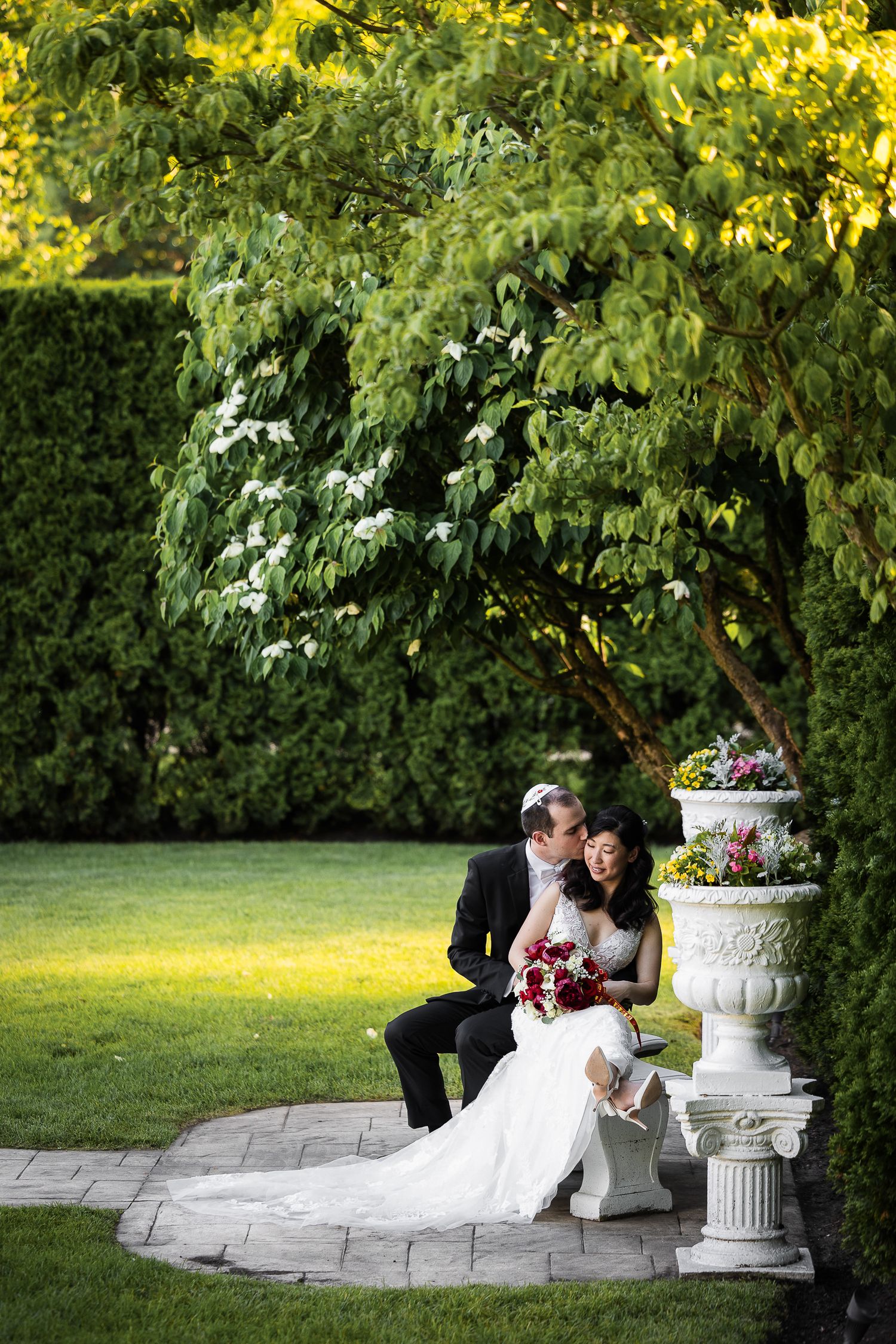 Newlywed couple shares intimate moments together on stone steps in a lush garden setting.