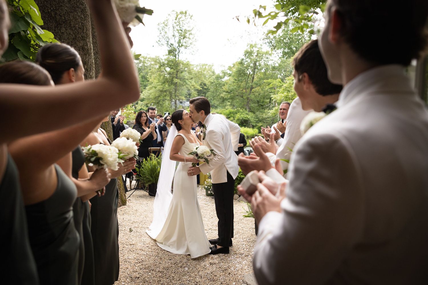 Wedding guests gather on garden path during outdoor celebration.