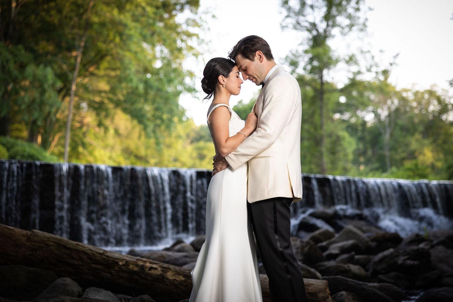 A romantic wedding photo session near a cascading waterfall surrounded by lush greenery.