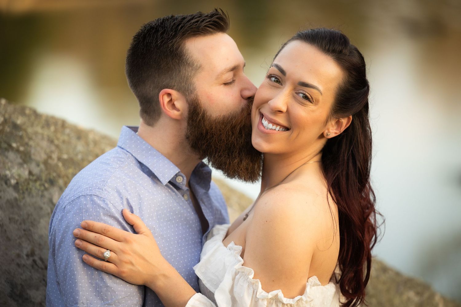 A romantic couple shares intimate moments together during an outdoor engagement photo session.