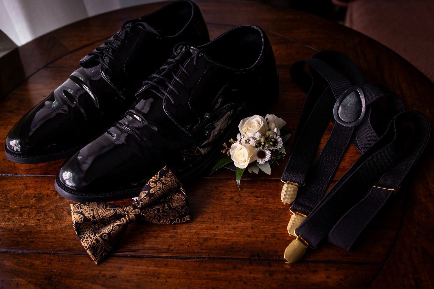 A black leather shoe with a broken sole sits on a dark wooden surface, revealing damaged internal construction details.