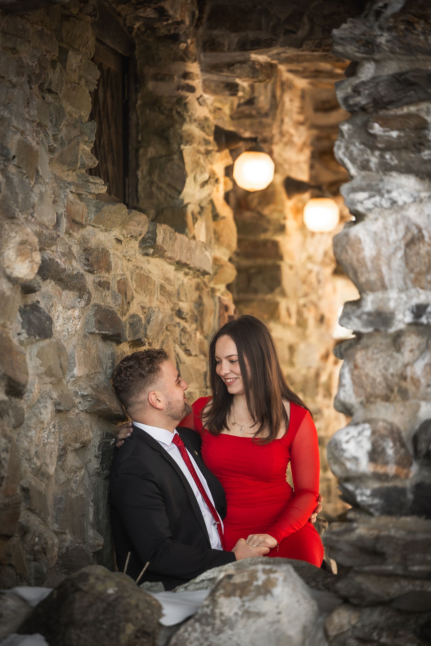 A couple shares romantic moments in a rustic stone grotto illuminated by warm glowing lights.