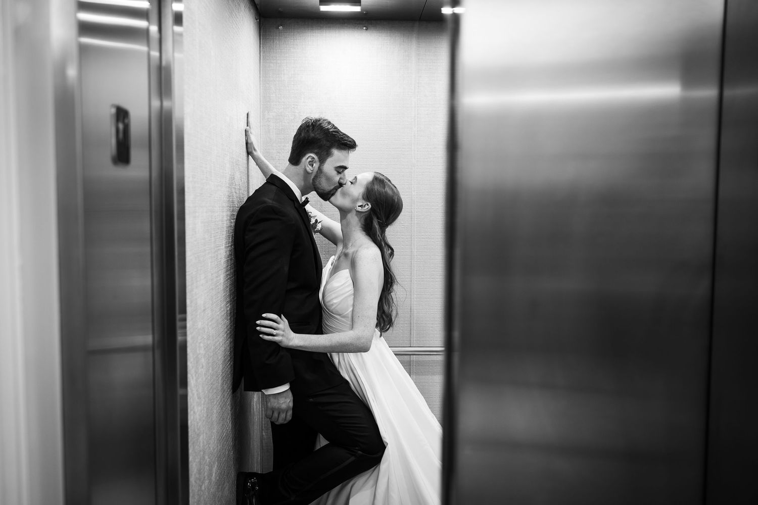 A romantic black and white moment between newlyweds in an elevator.