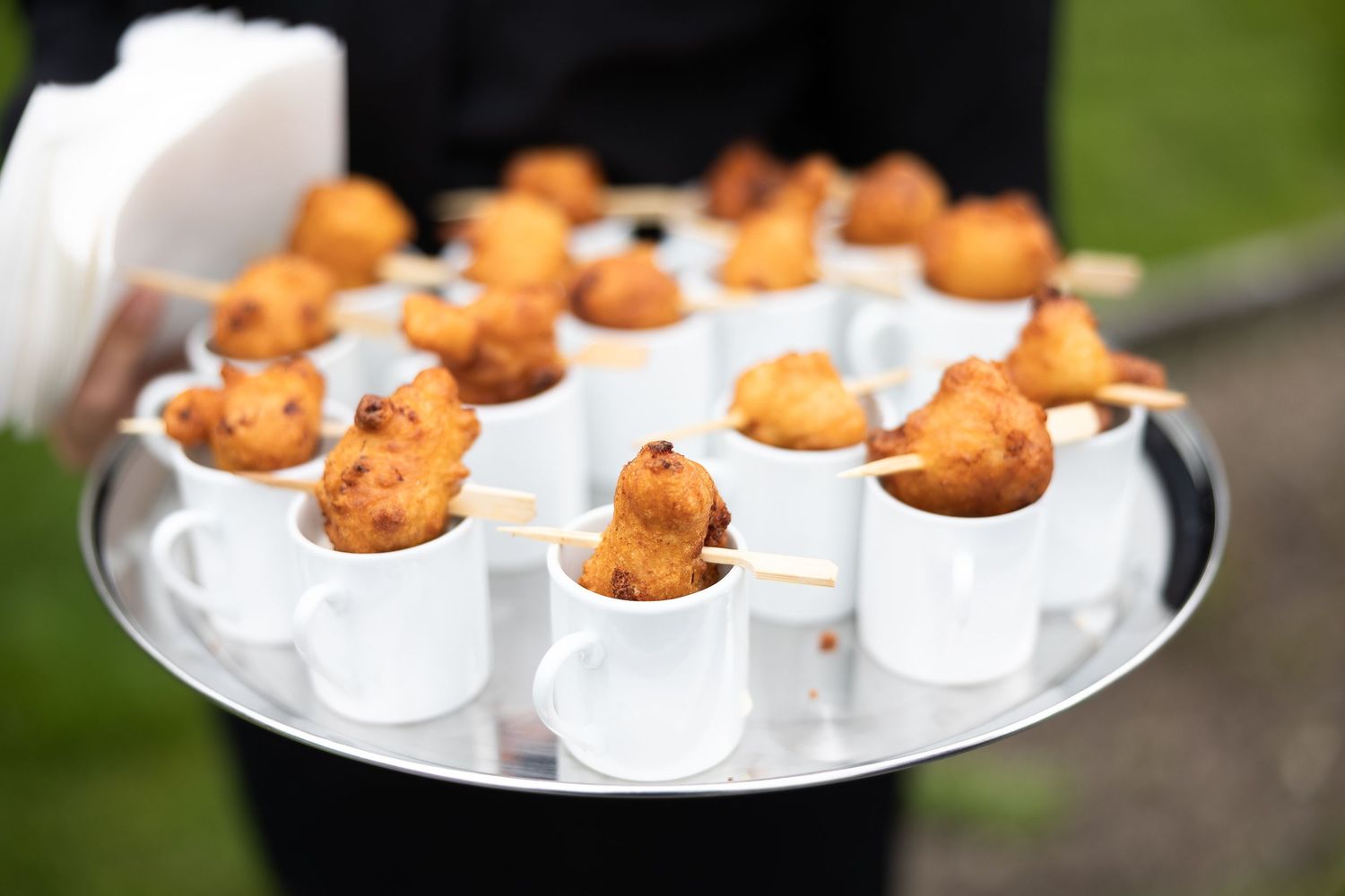 Elegant appetizers served in small white ceramic cups arranged on serving platters at an upscale event.