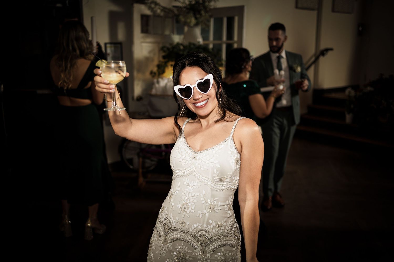 A person wearing a white lace sleeveless top dances at a social gathering or party.