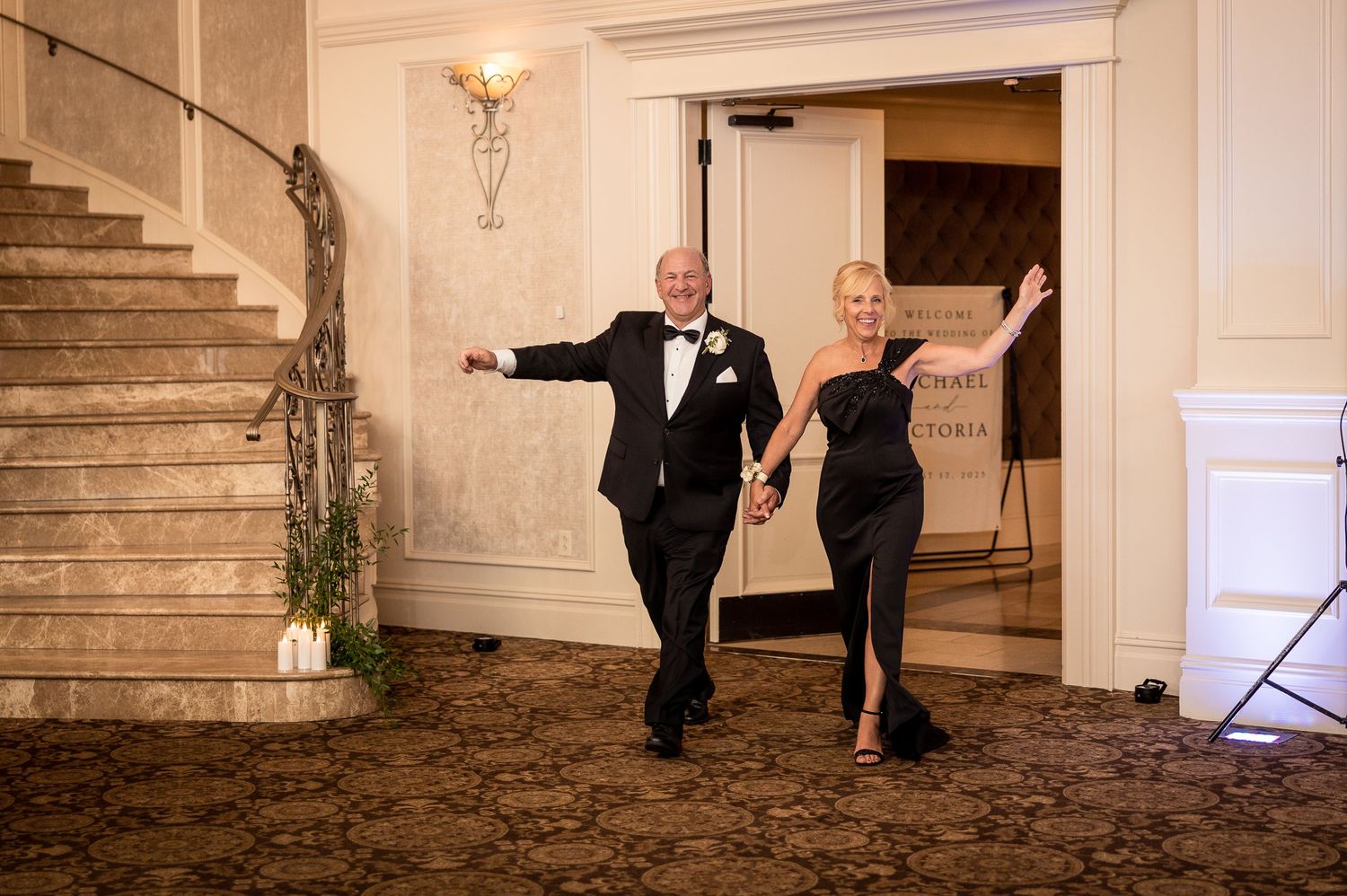 Elegant wedding couple dancing together on grand marble staircase in formal attire.