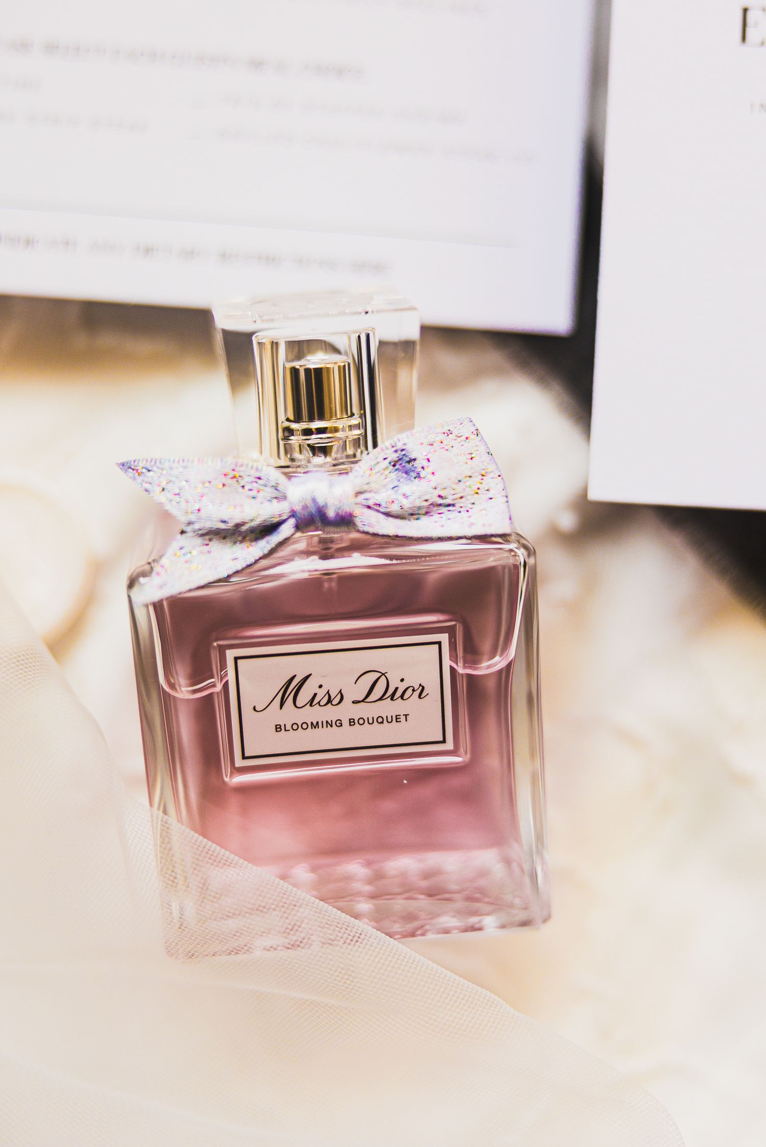 Miss Dior perfume bottle displayed on white surface with soft focus.