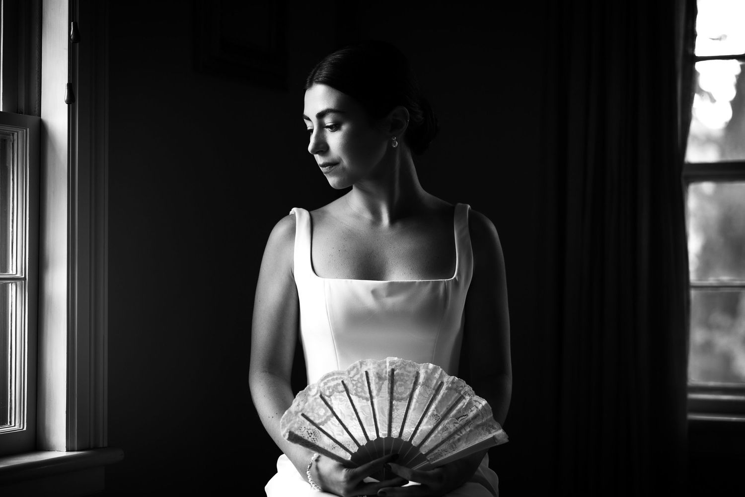 Dramatic black and white silhouette of person in formal attire by window.