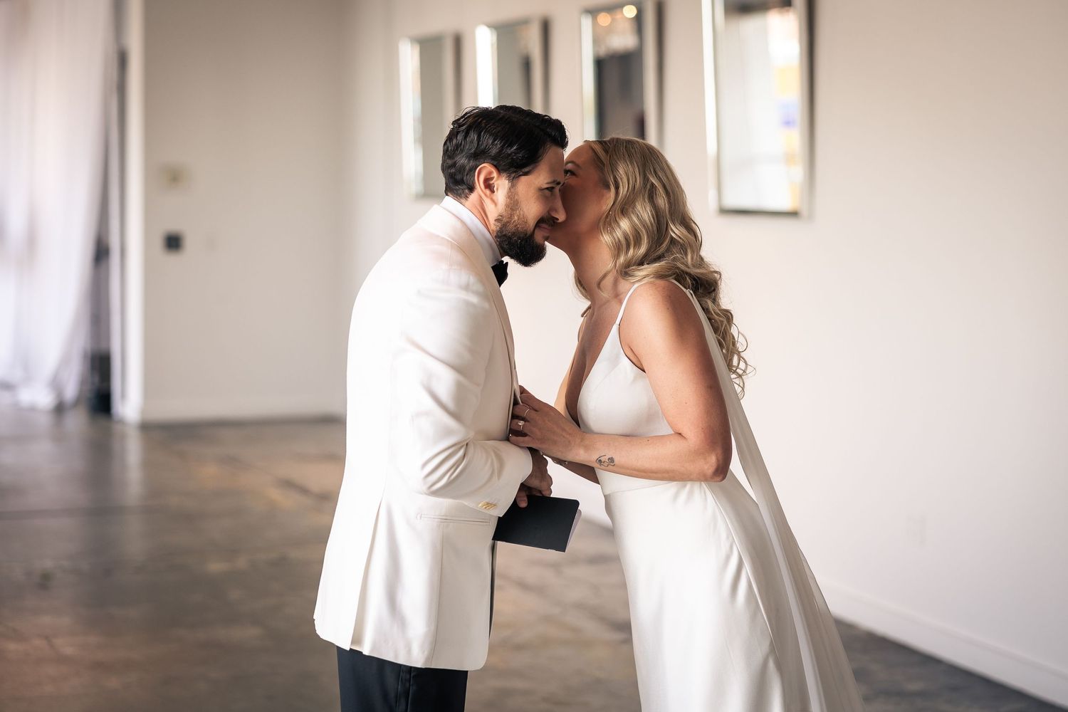 A couple shares an intimate first look moment in an elegant white industrial wedding venue space.