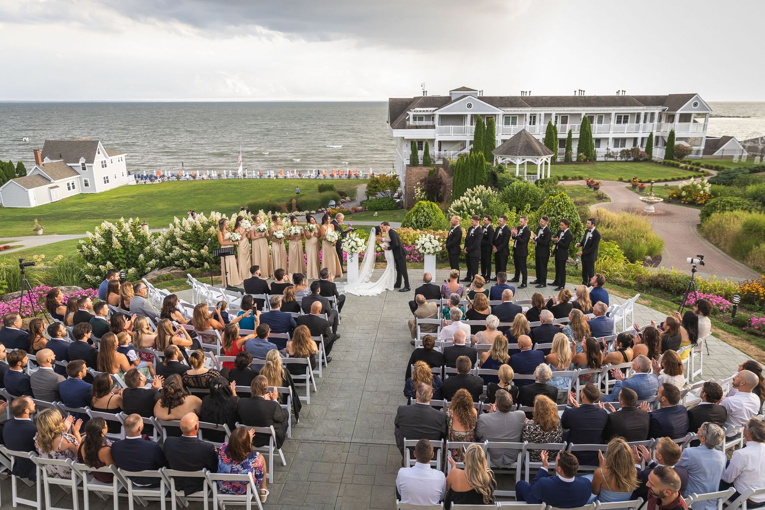 Oceanfront wedding ceremony setup with white chairs and coastal backdrop.