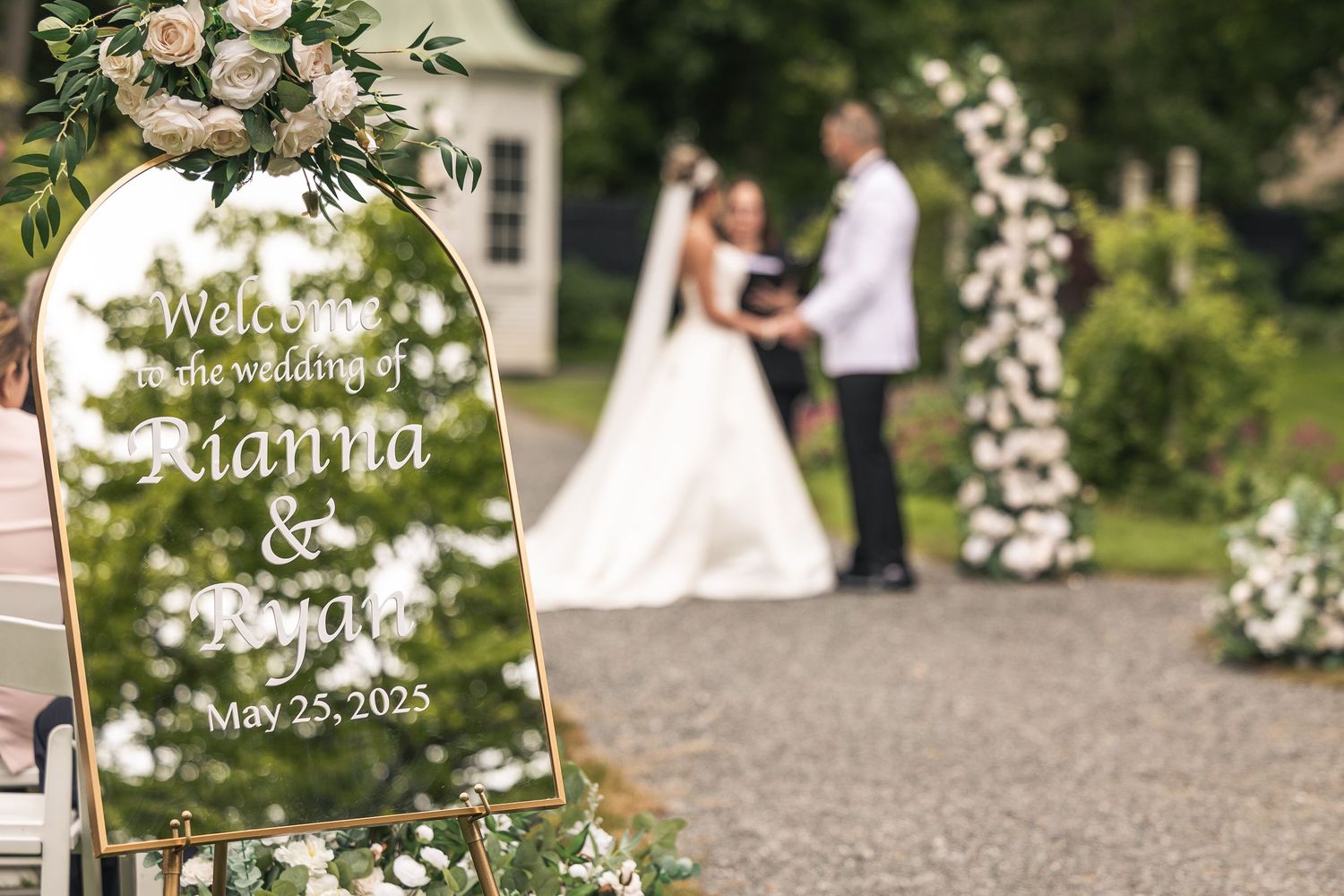 Outdoor wedding ceremony site with floral arch and garden setting.