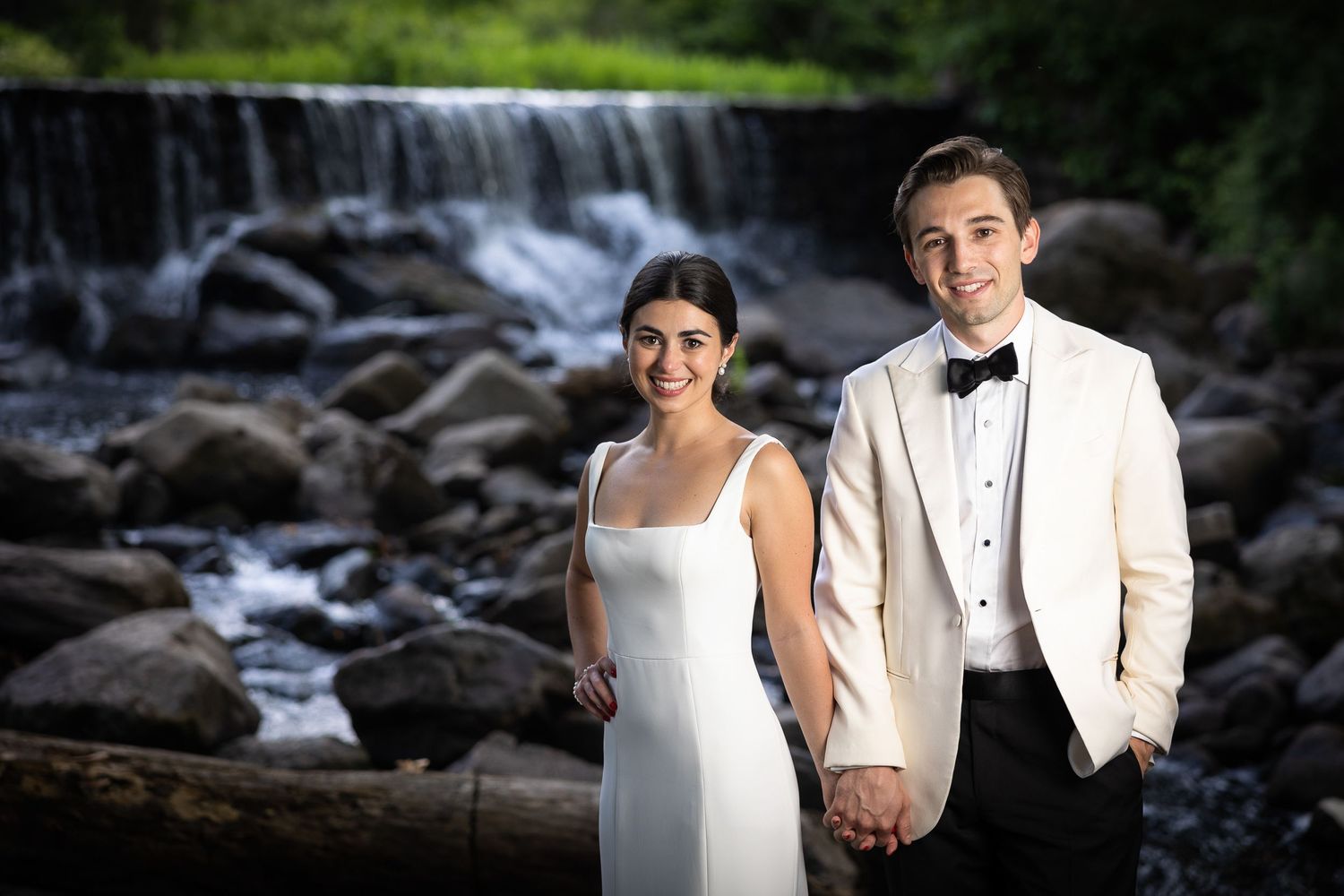Elegant wedding portraits captured against a natural waterfall and stone backdrop.