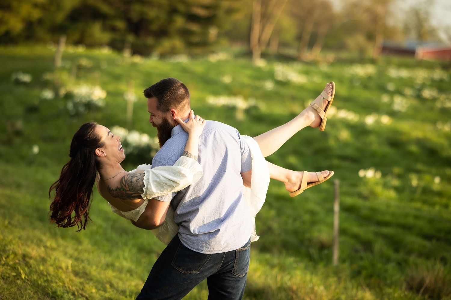 A couple dances together on a grassy field during golden hour with romantic, flowing movements.