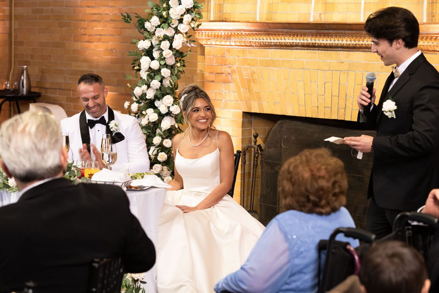 Wedding reception venue decorated with white floral arrangements and warm lighting.