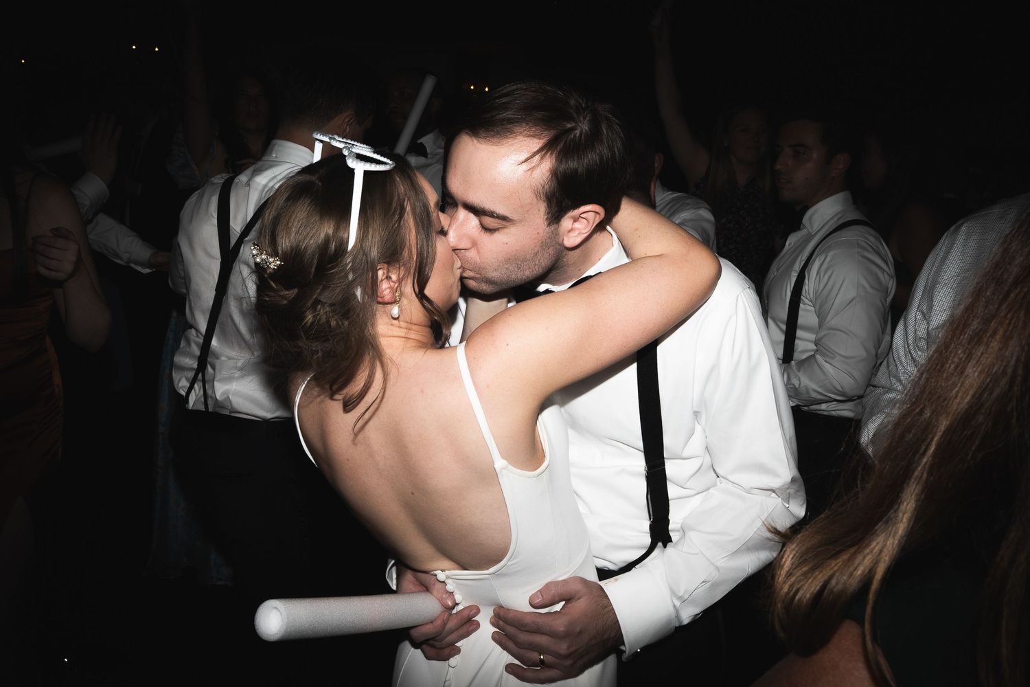 A romantic dance floor moment between newlyweds sharing a kiss at their wedding reception.