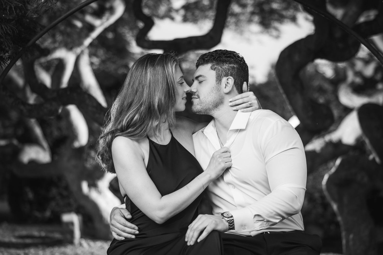 A romantic black and white photo series showing a couple embracing and dancing together in an outdoor setting.