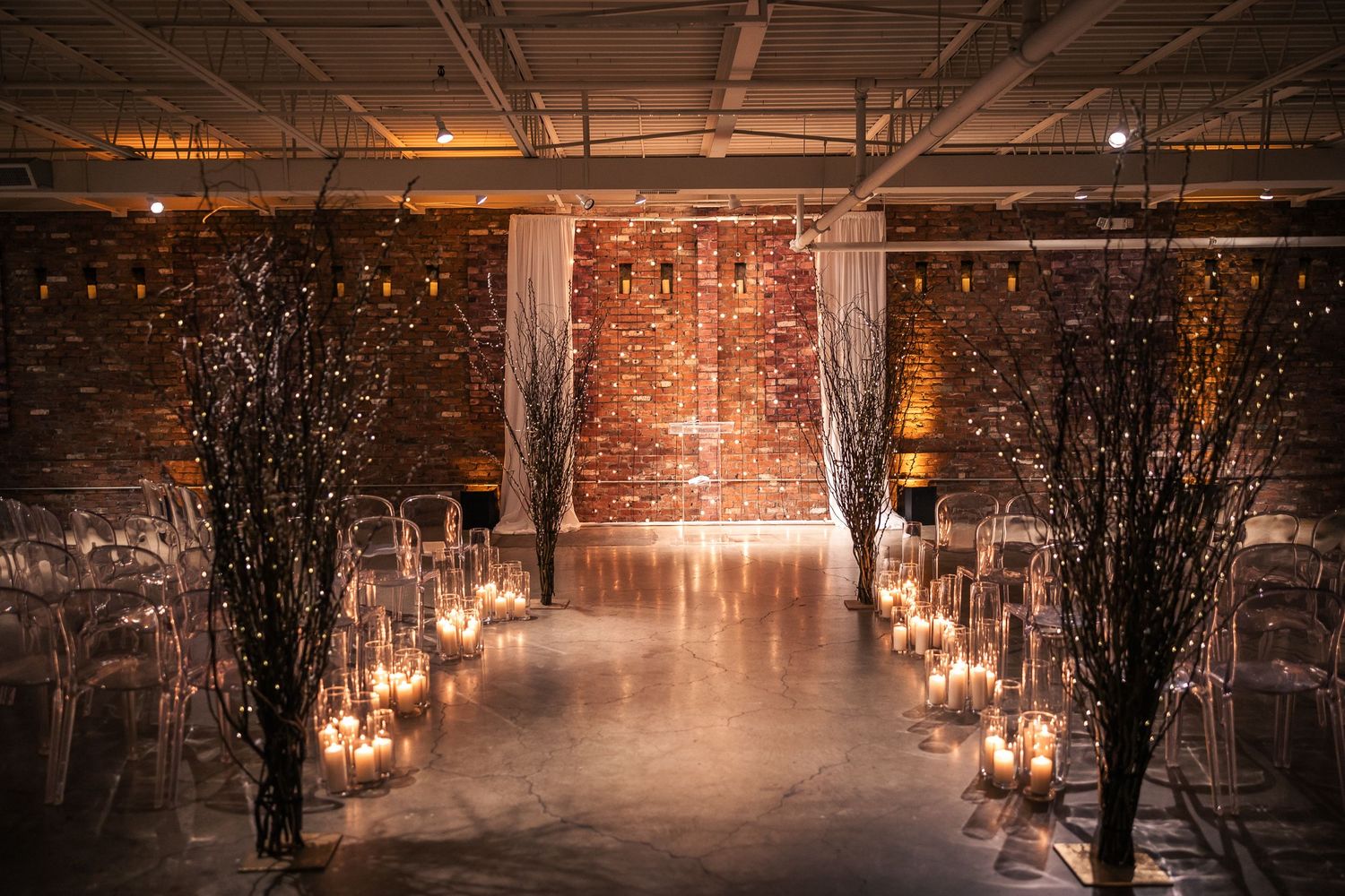 Snow-covered pathway illuminated by glowing lanterns and twinkling lights creates a magical winter evening scene.