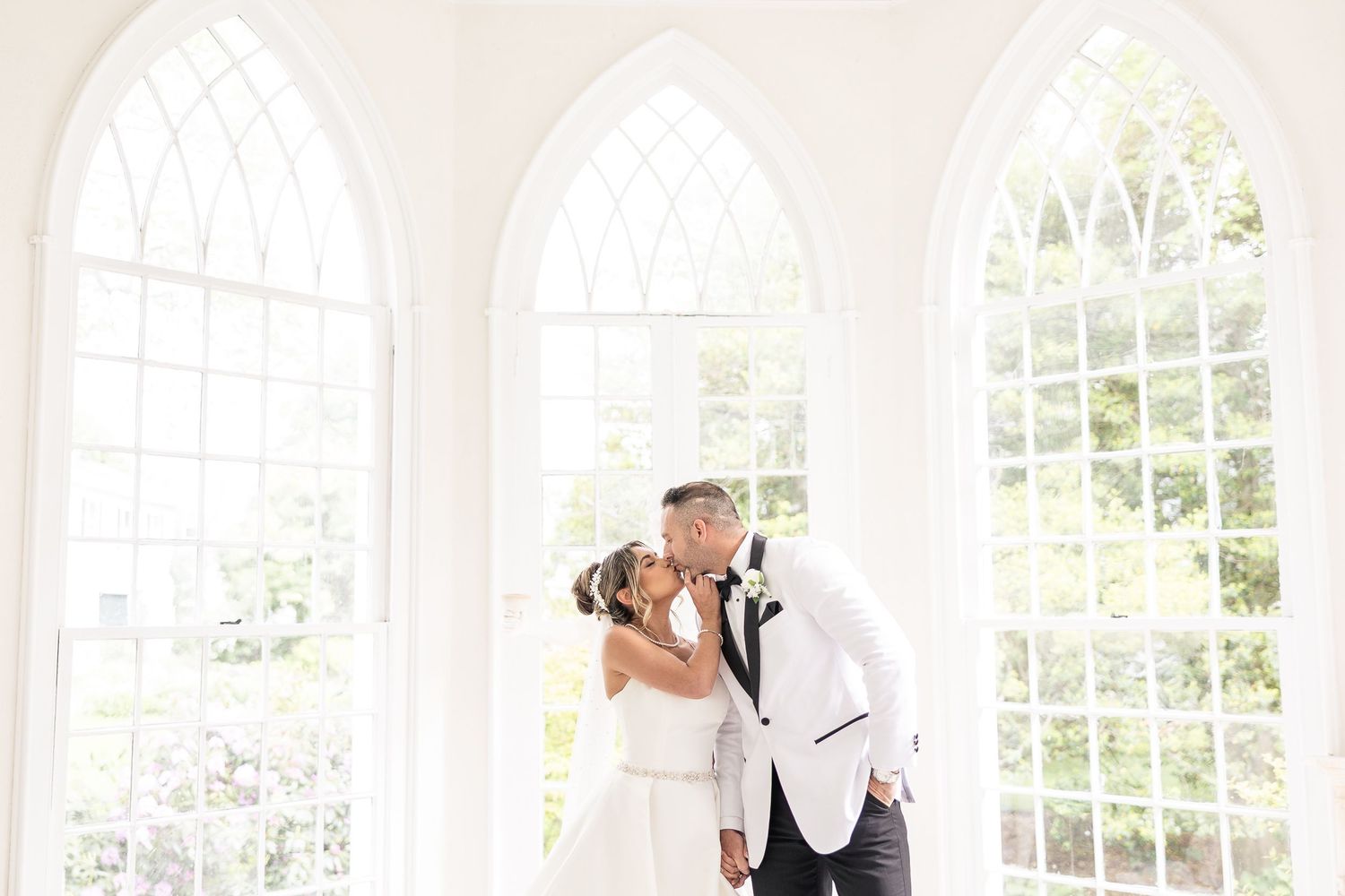 Elegant white wedding venue interior with arched windows and natural light.