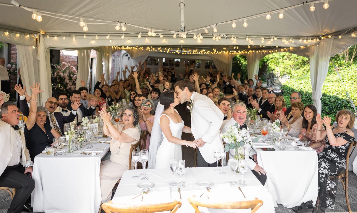 Wedding reception under a tent with guests celebrating the newlyweds.
