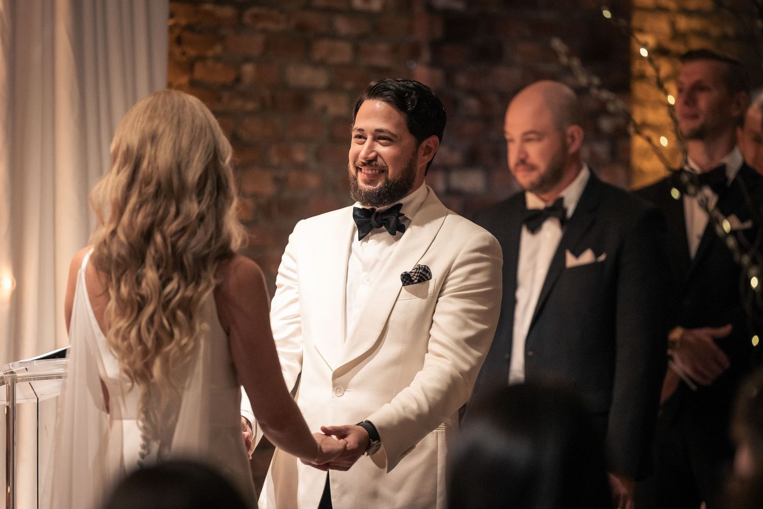 A joyous celebration at an elegant wedding reception with people laughing and socializing in formal attire.