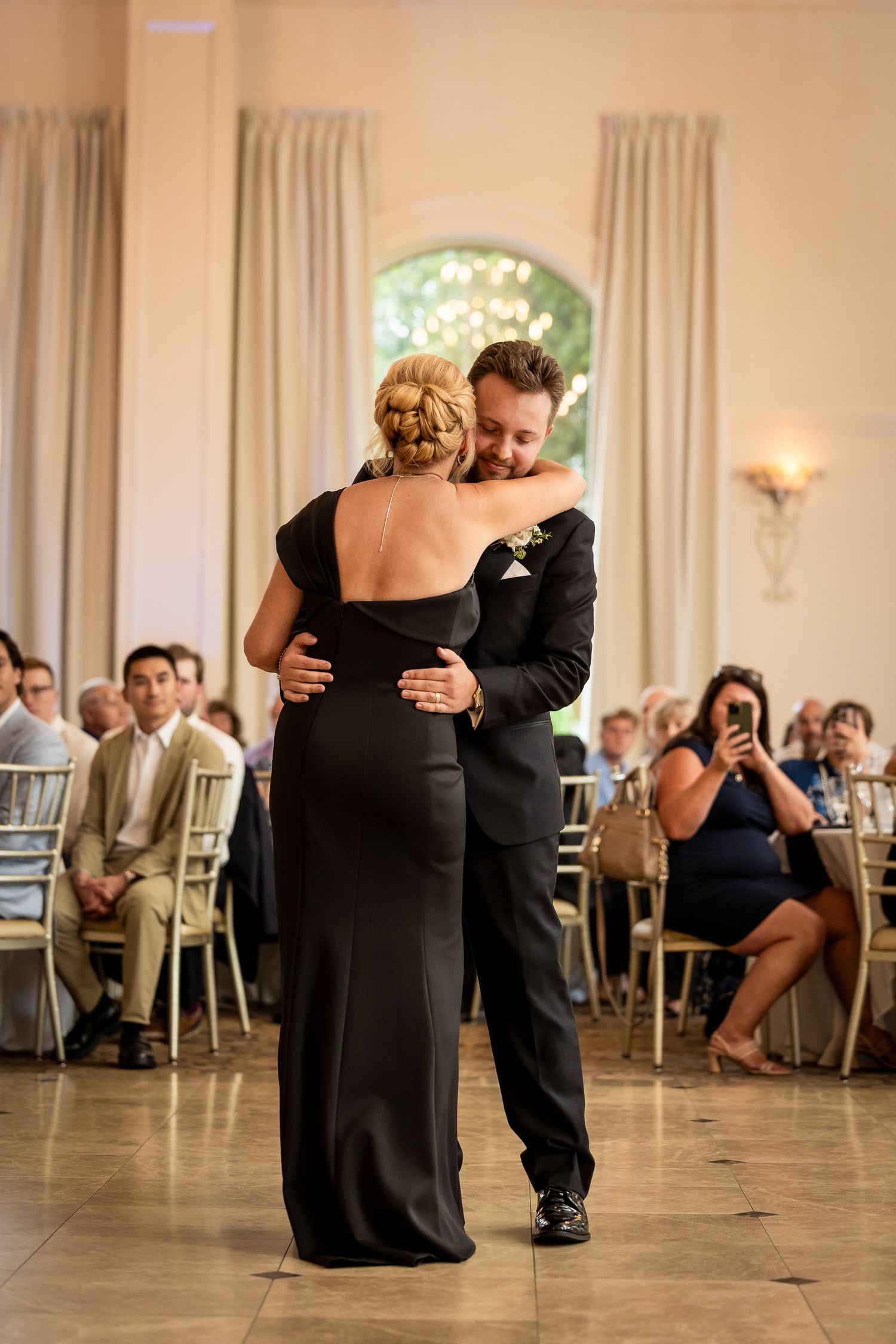 Couples dance together during an elegant wedding reception in a warm-lit ballroom.
