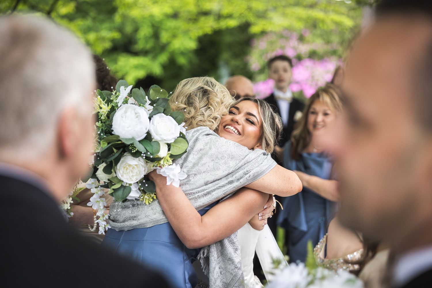Wedding party members celebrating with flowers in an outdoor garden setting.