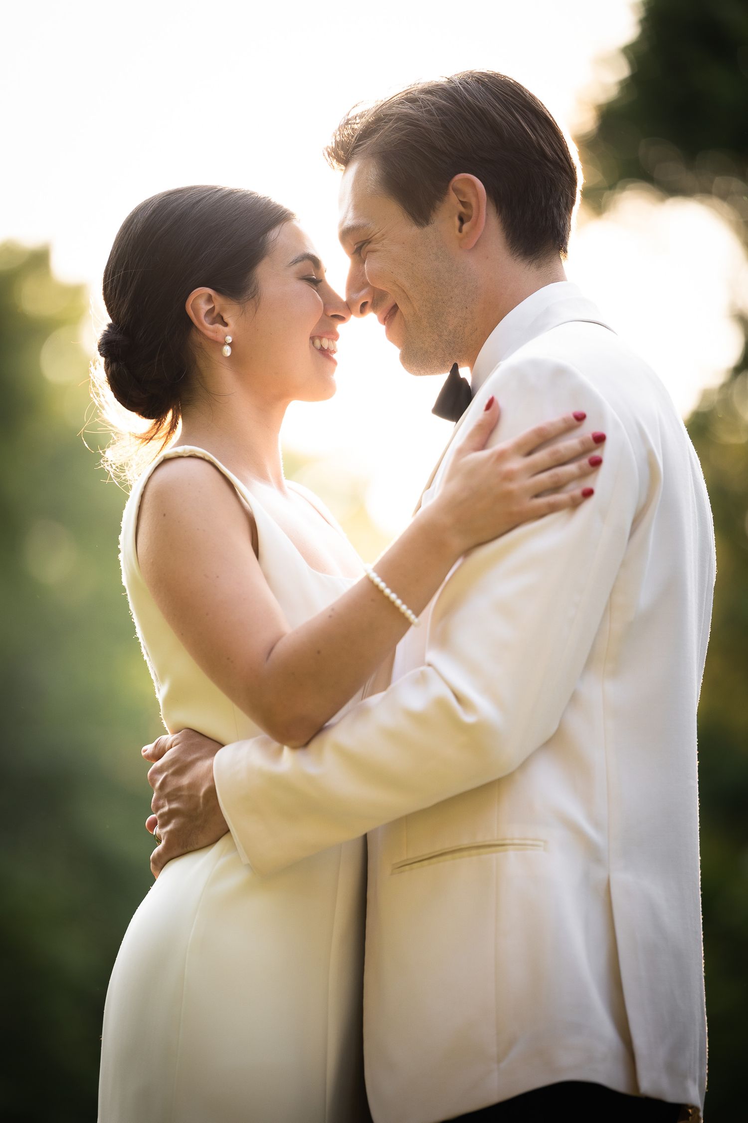 Romantic moment captured between couple in formal attire during sunset wedding celebration.