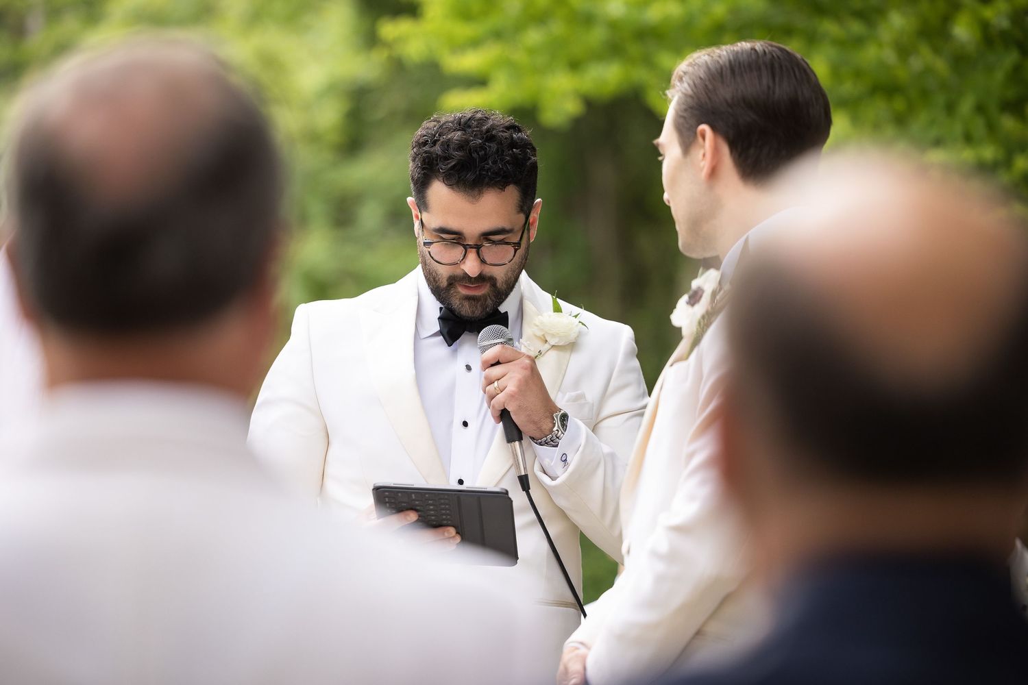 Wedding ceremony participants stand in line during outdoor garden event.