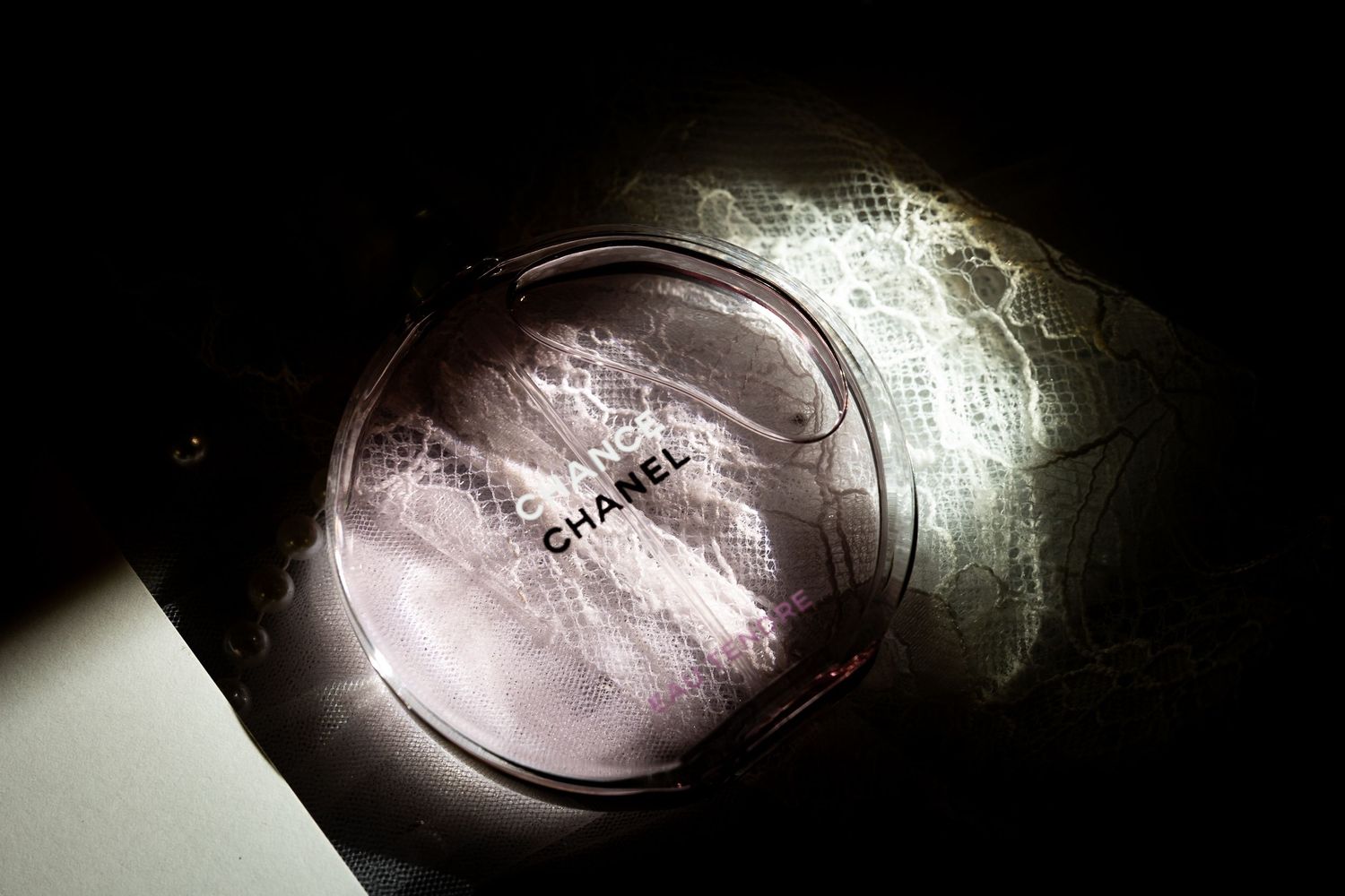 Artistic close-up shot of a pink compact powder makeup product in dramatic lighting.