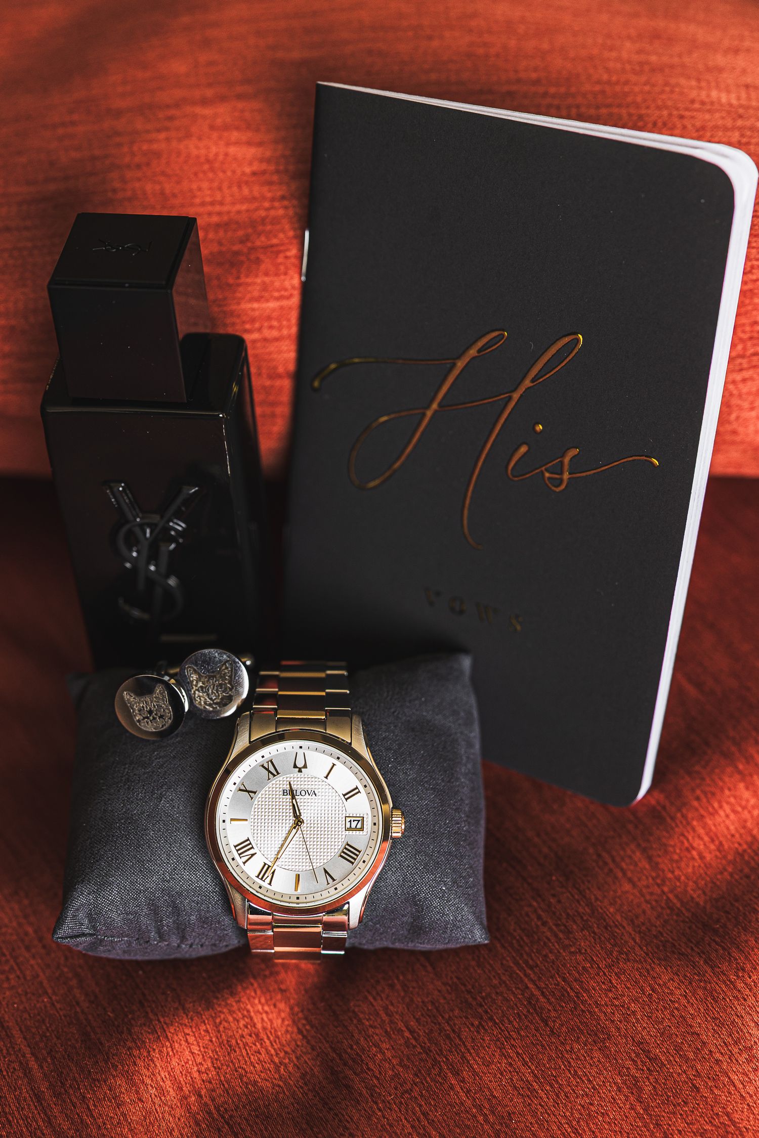 Elegant watch and wedding accessories displayed on red fabric.