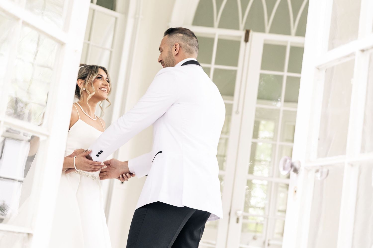 Intimate moments captured in bright sunlit room with white architectural details.