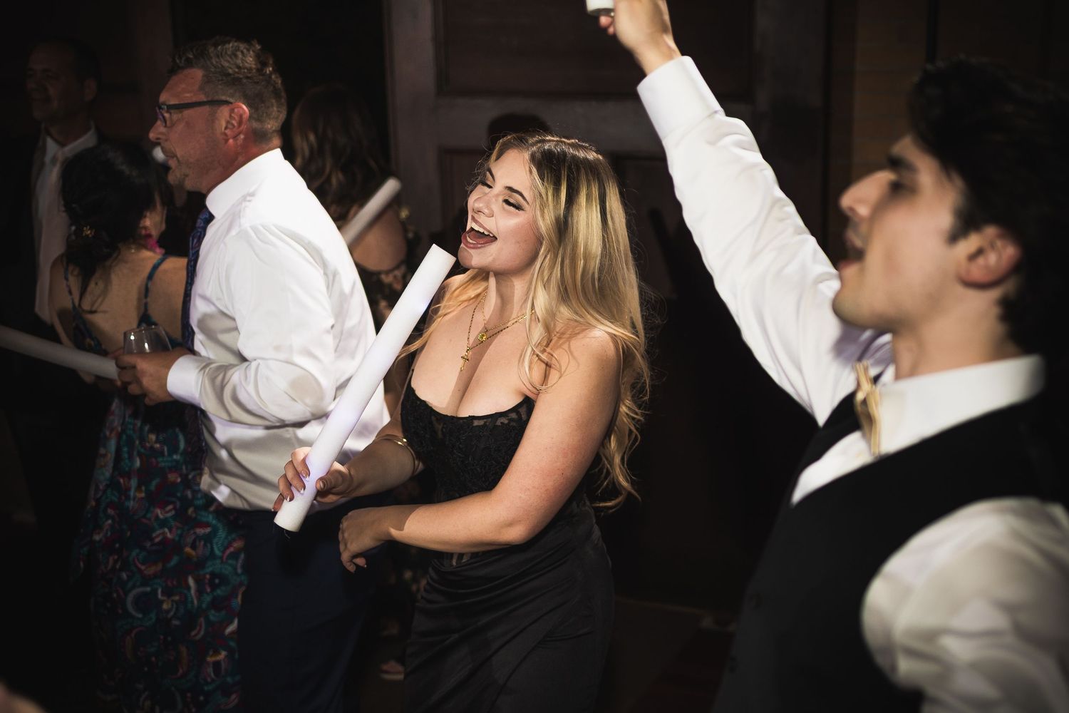 Guests dancing and celebrating at a dimly lit wedding reception party.