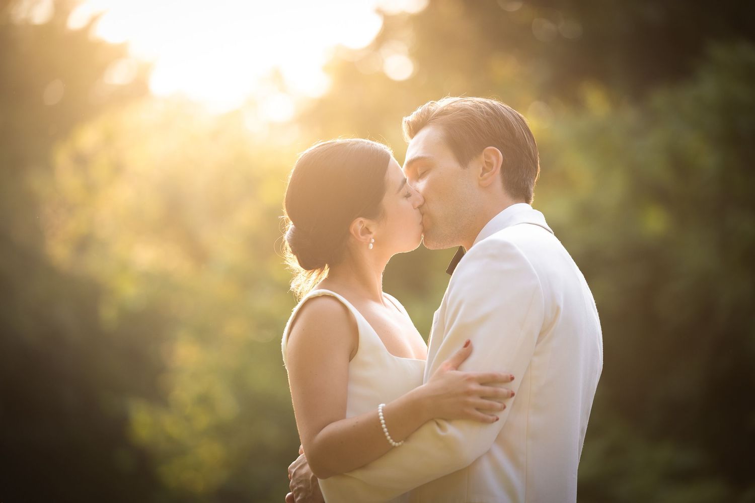 Intimate sunset portrait of couple embracing in formal wedding attire.