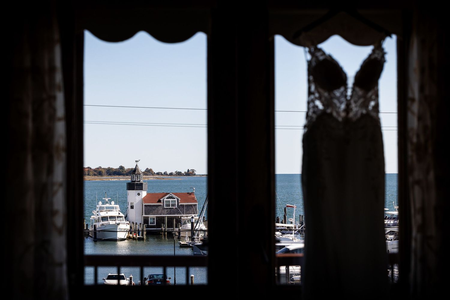 Silhouetted boats and docks at a marina viewed through dark columns at sunset.