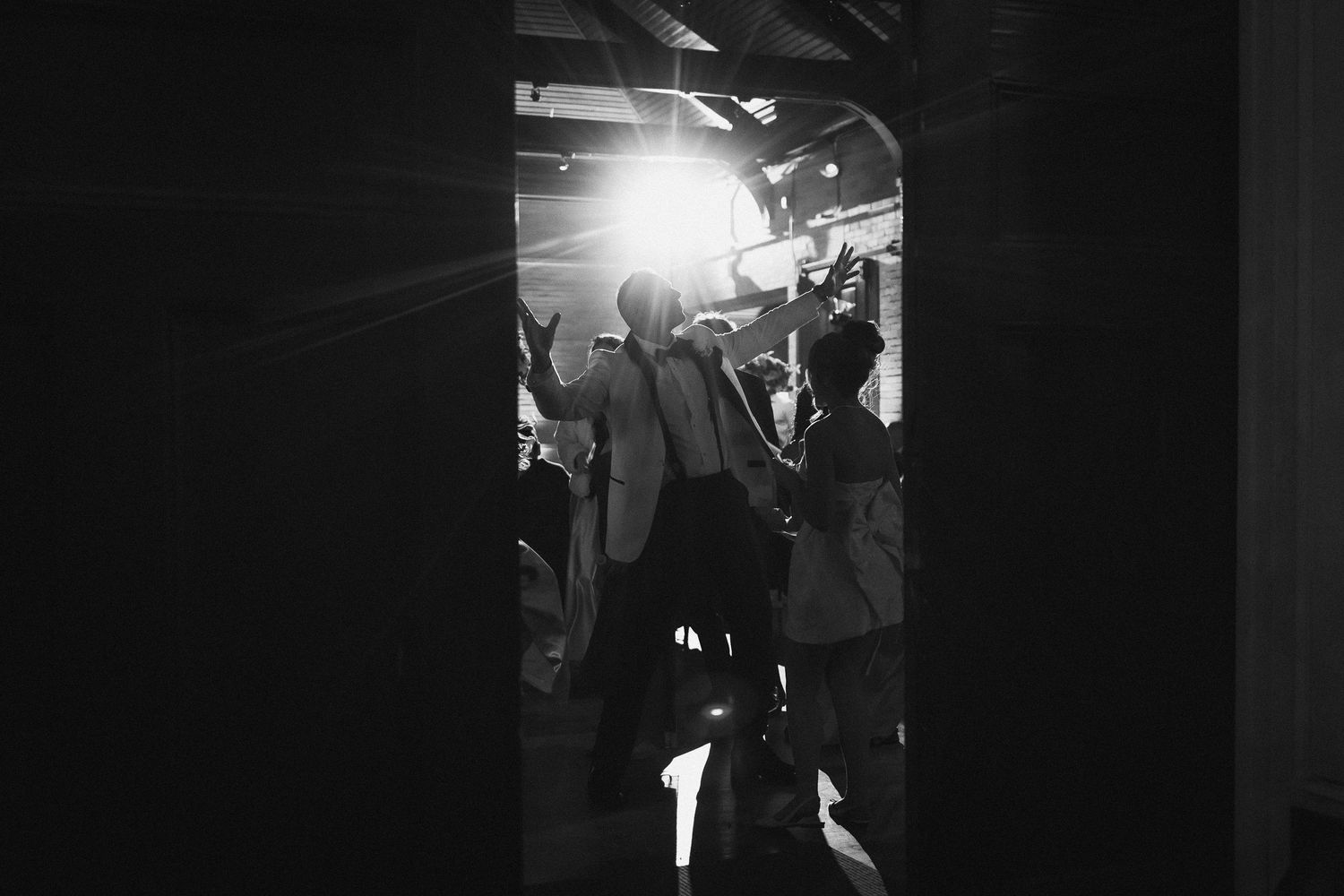 Silhouetted wedding reception dancing captured in dramatic lighting.