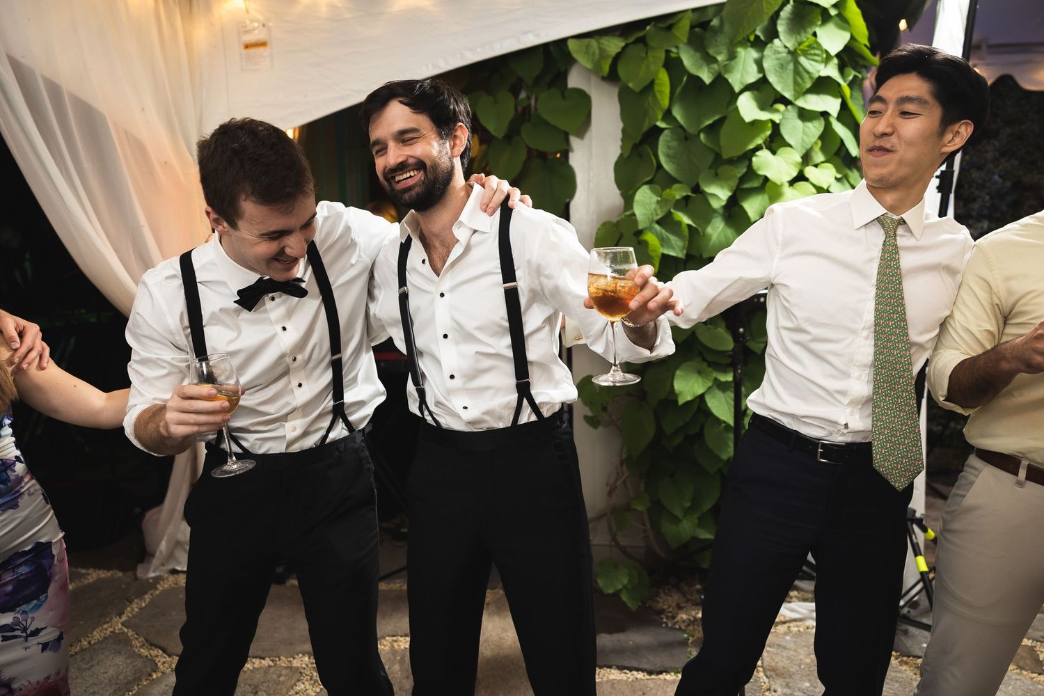 Wedding party members in formal attire dancing and celebrating together.